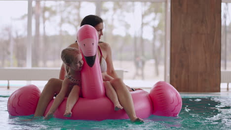 Kleines-Mädchen-Und-Ihre-Mutter-Sitzen-Auf-Einem-Aufblasbaren-Flamingo-Im-Schwimmbad-Und-Ruhen-Sich-Im-Familien-Wellnesscenter-Aus